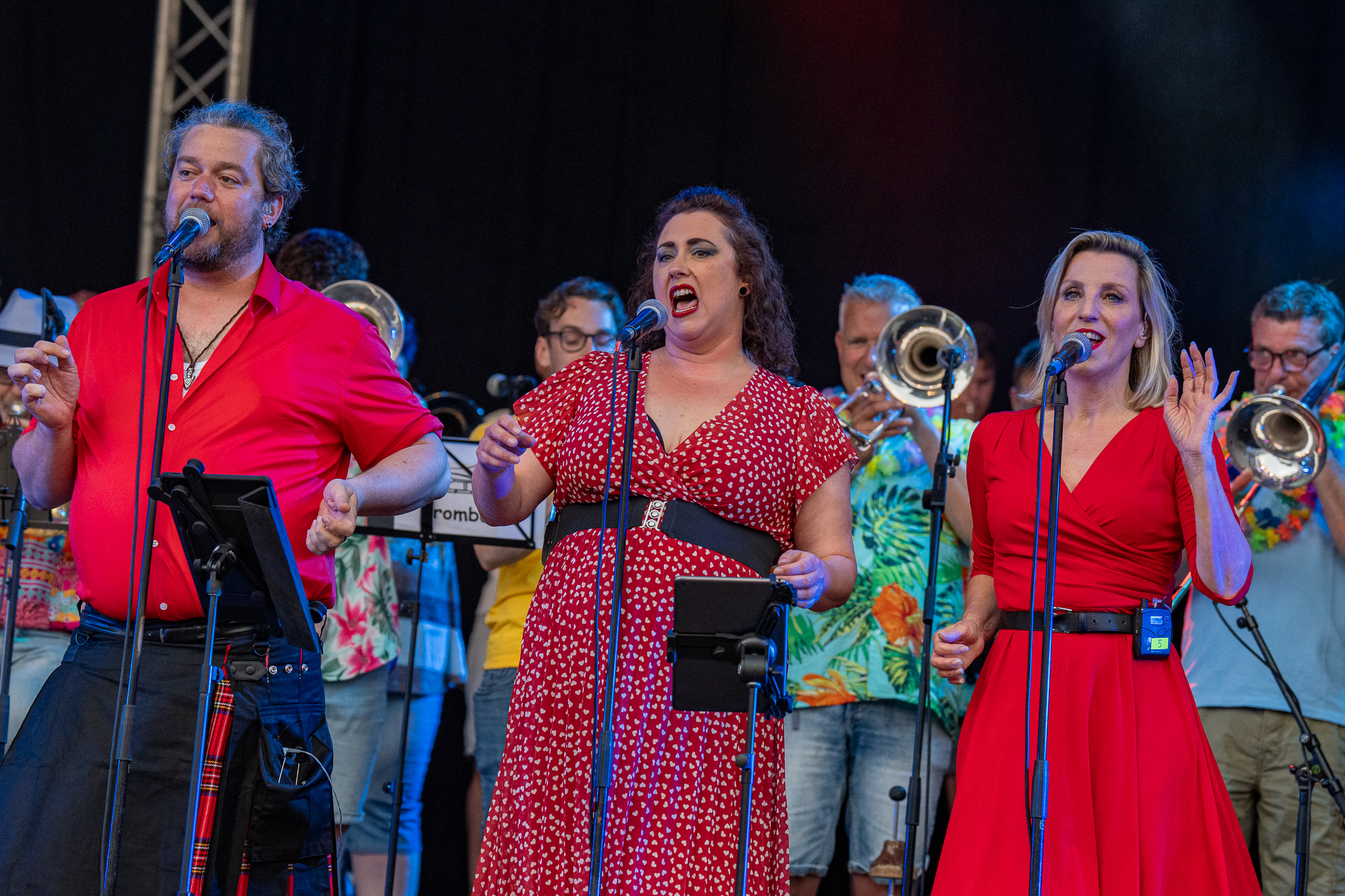 Zangers van Vocalicious in het rood achter de microfoon op het Spanjaardsgat Festival