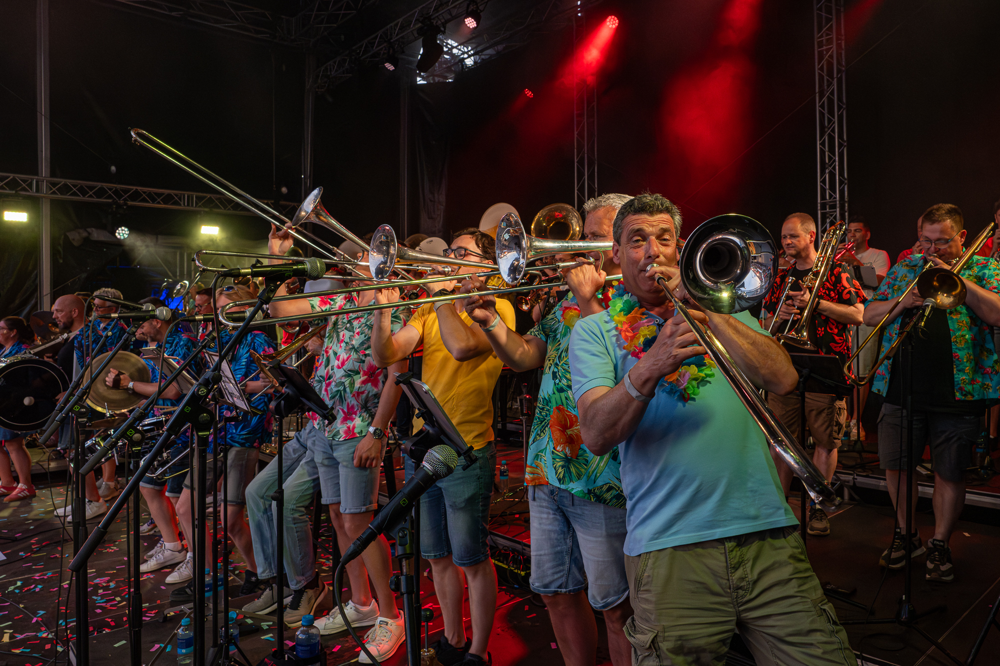De blazerssectie in actie onder rood podiumlicht op het Spanjaardsgat Festival